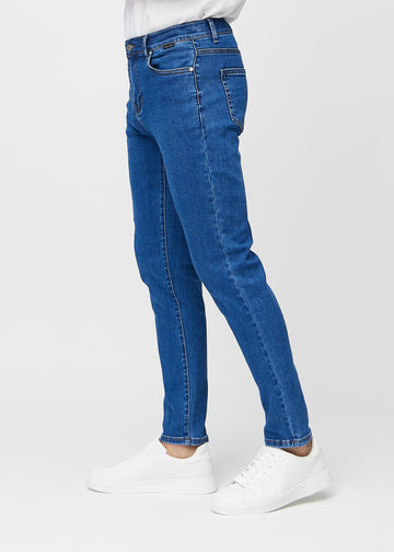 Mørkeblå denimjeans i slim fit sett fra siden på en modell.