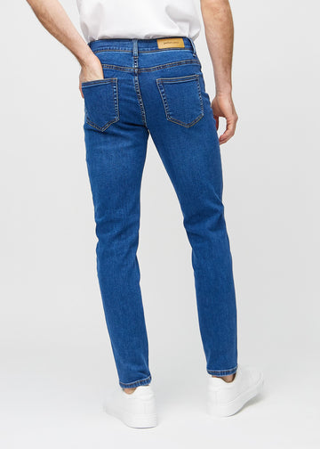 Mørkeblå denimjeans i slim fit sett bakfra for å vise hele produktet.
