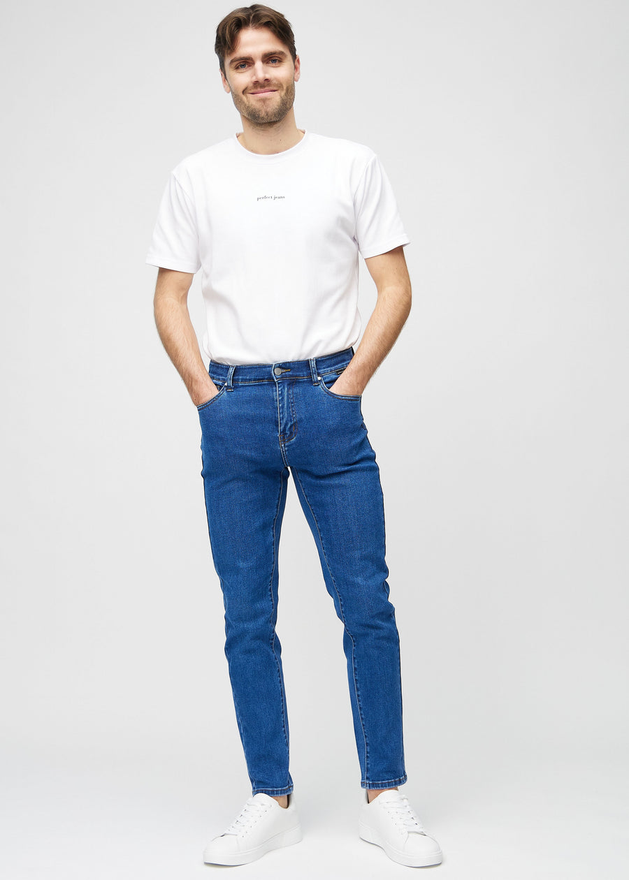 Helbilde av en modell i mørkeblå denimjeans i slim fit.