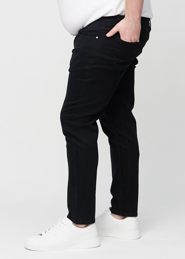 Svarte jeans i slim fit sett fra siden på en plus-size-modell.