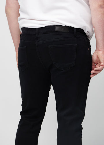 Nærbilde bakfra av svarte jeans i slim fit på en plus-size-modell som viser detaljer.