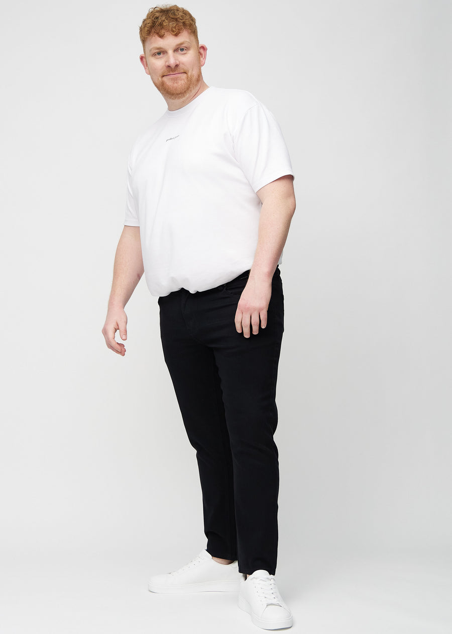 Helbilde av en plus-size-modell i svarte jeans i slim fit.