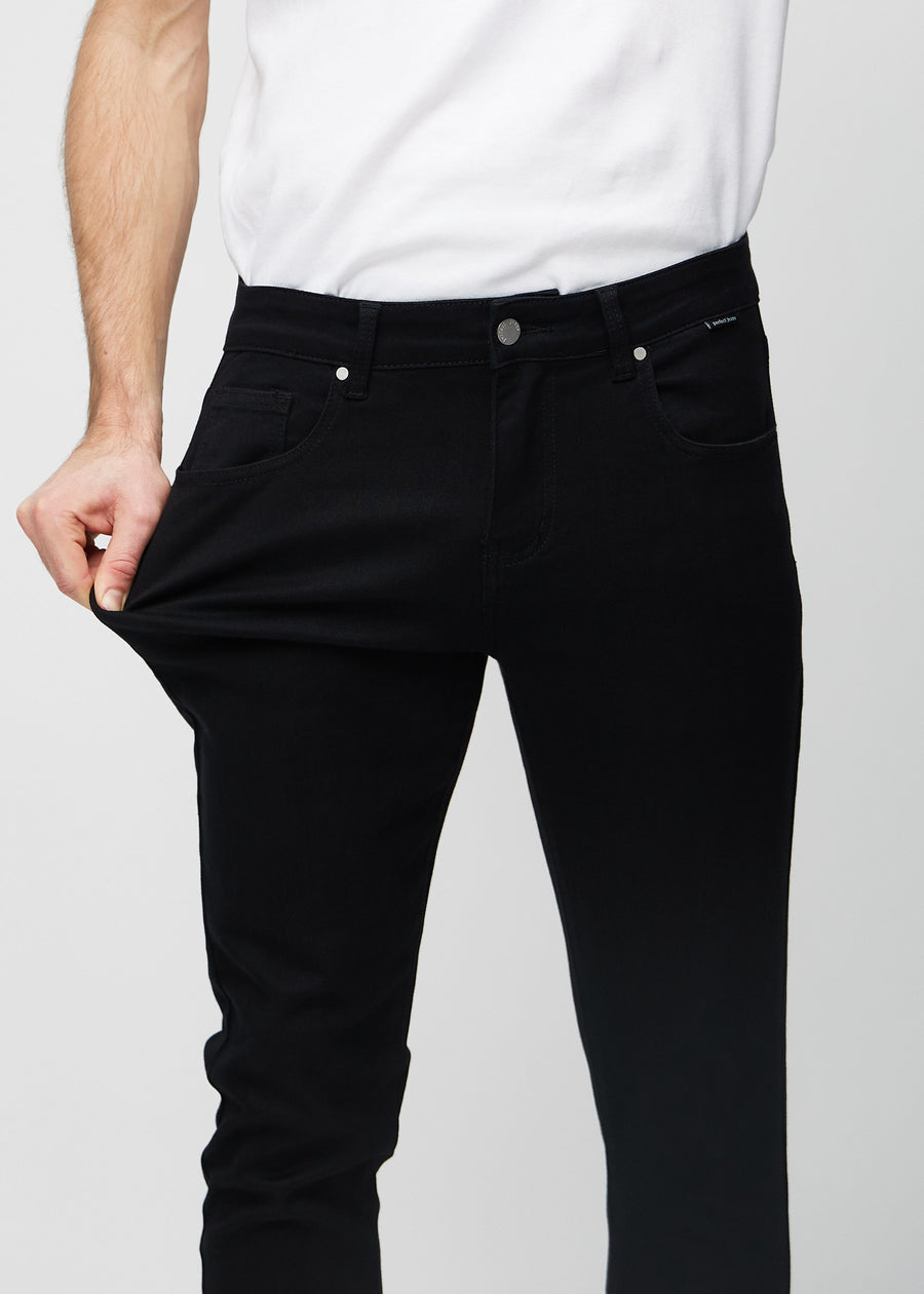 Modell strekker jeansene ved låret for å vise materialets stretch.