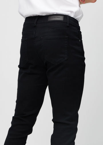 Nærbilde bakfra av svarte jeans i slim fit som viser detaljer.