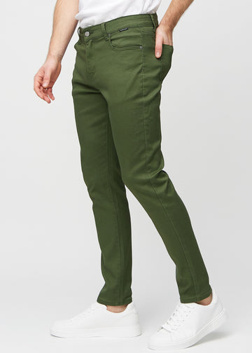 Mørkegrønne jeans i slim fit sett fra siden på en modell.