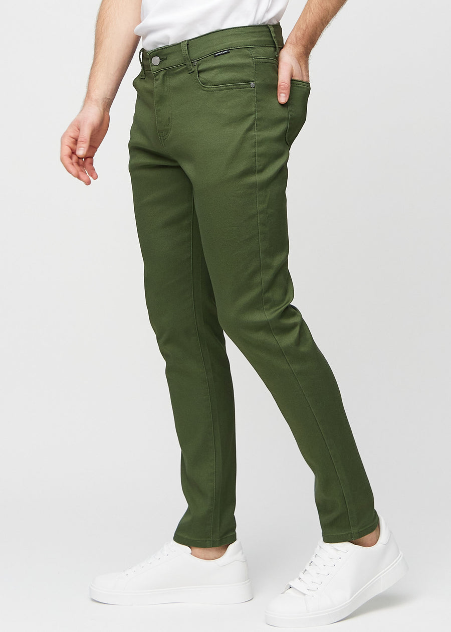 Mørkegrønne jeans i slim fit sett fra siden på en modell.