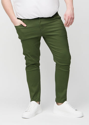 Mørkegrønne jeans i slim fit, modellnavn Renewals, som sitter tett langs bena på en plus-size-modell, sett forfra.