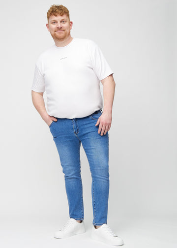 Helbilde av en plus-size-modell i blå denimjeans i slim fit.
