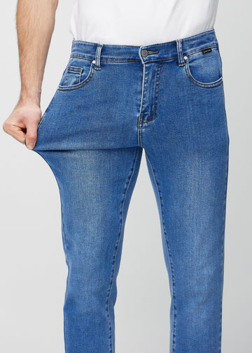 Modell strekker jeansene ved låret for å vise materialets stretch.