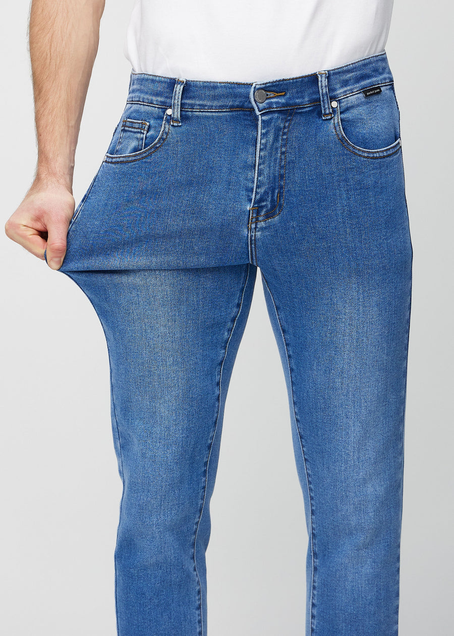 Modell strekker jeansene ved låret for å vise materialets stretch.