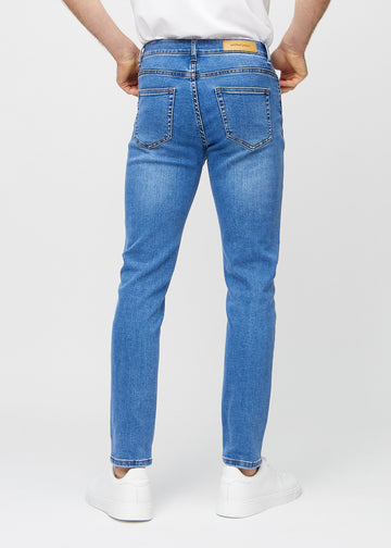 Blå denimjeans i slim fit sett bakfra for å vise hele produktet.