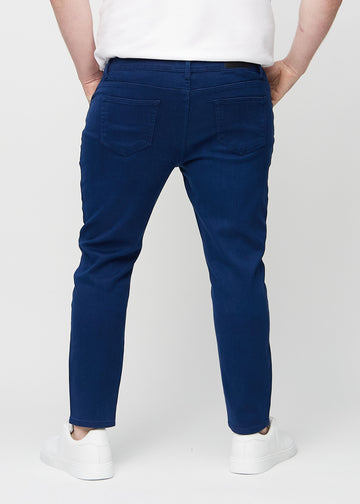 Mørkeblå jeans i slim fit sett bakfra på en plus-size-modell for å vise hele produktet.