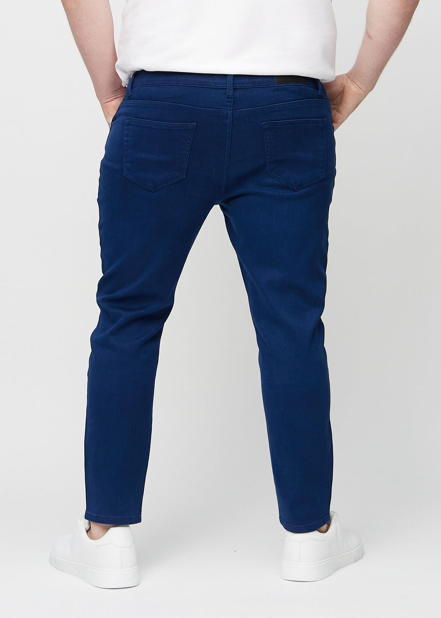 Mørkeblå jeans i slim fit sett bakfra på en plus-size-modell for å vise hele produktet.