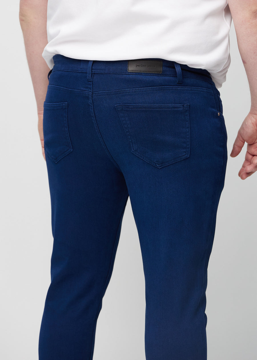 Nærbilde bakfra av mørkeblå jeans i slim fit på en plus-size-modell som viser detaljer.