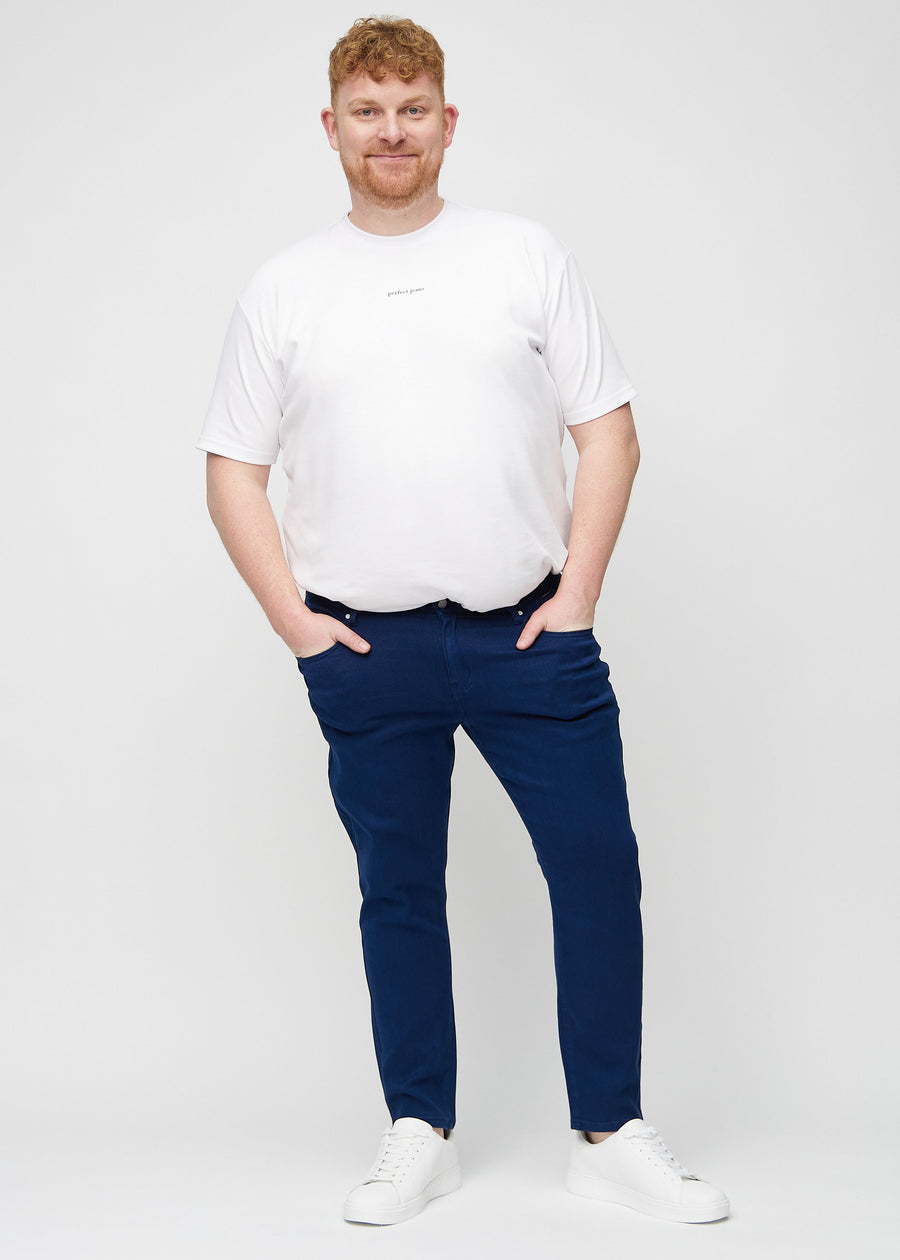 Helbilde av en plus-size-modell i mørkeblå jeans i slim fit.