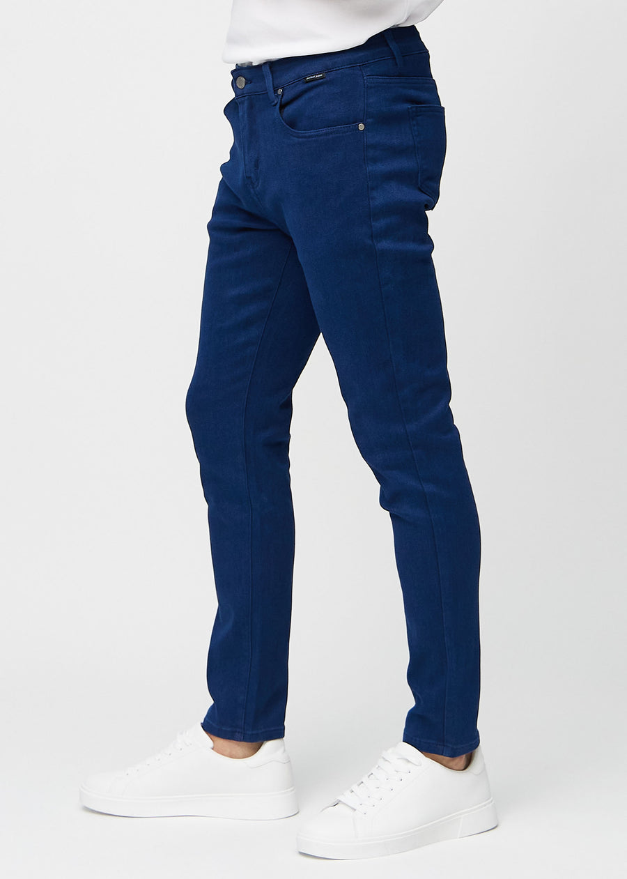 Mørkeblå jeans i slim fit sett fra siden på en modell.