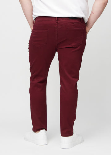 Mørkerøde jeans i slim fit sett bakfra på en plus-size-modell for å vise hele produktet.