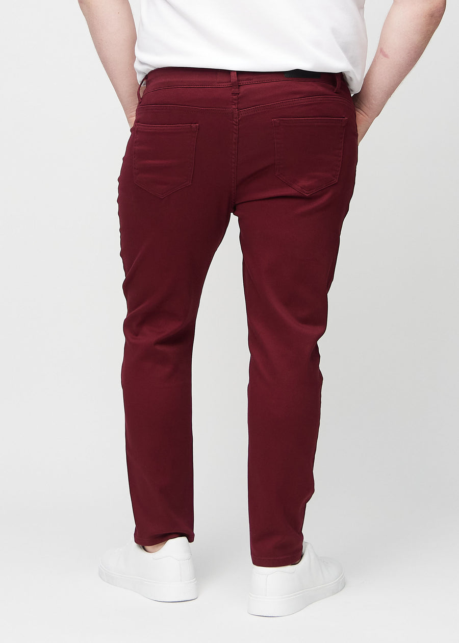 Mørkerøde jeans i slim fit sett bakfra på en plus-size-modell for å vise hele produktet.