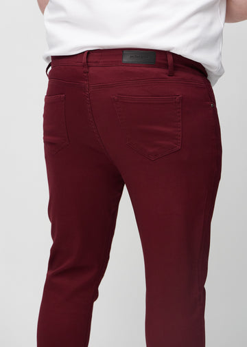 Nærbilde bakfra av mørkerøde jeans i slim fit på en plus-size-modell som viser detaljer.