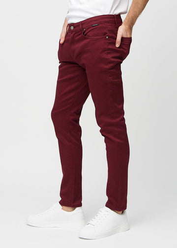 Mørkerøde jeans i slim fit sett fra siden på en modell.