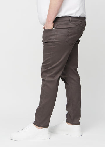 Gråbrune jeans i slim fit sett fra siden på en plus-size-modell.