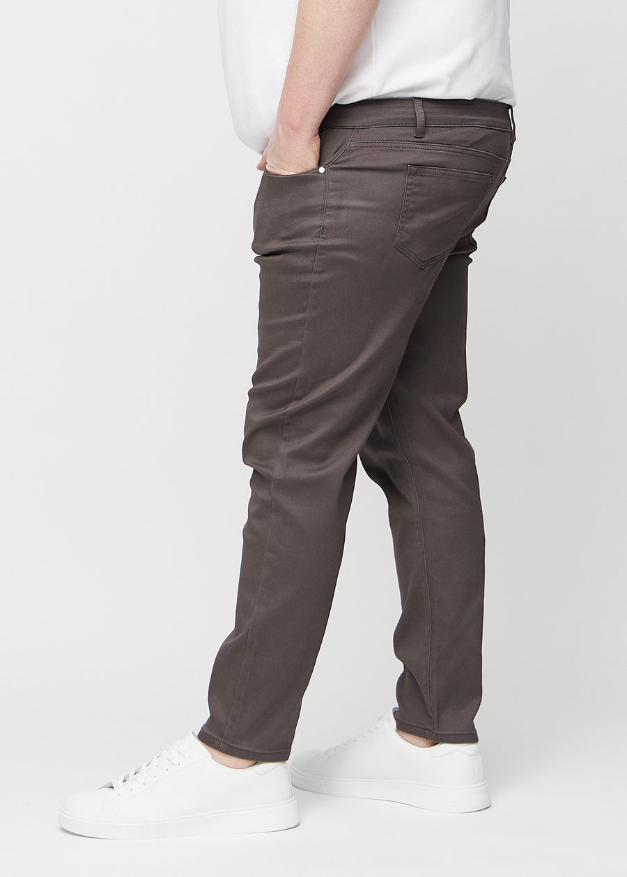 Gråbrune jeans i slim fit sett fra siden på en plus-size-modell.