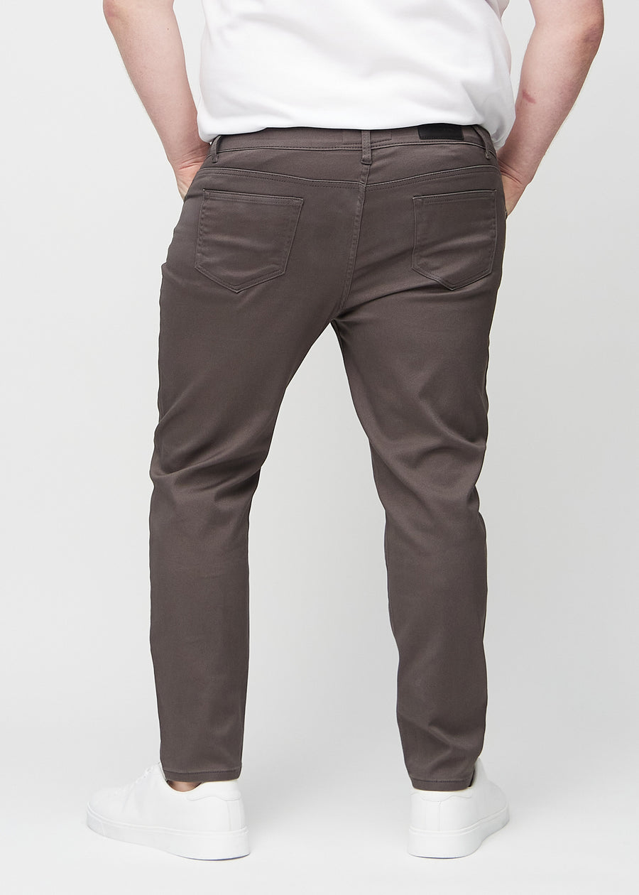 Gråbrune jeans i slim fit sett bakfra på en plus-size-modell for å vise hele produktet.