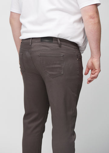 Nærbilde bakfra av gråbrune jeans i slim fit på en plus-size-modell som viser detaljer.