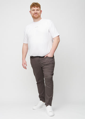 Helbilde av en plus-size-modell i gråbrune jeans i slim fit.