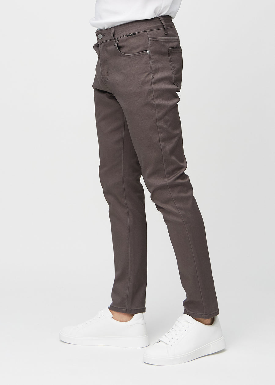 Gråbrune jeans i slim fit sett fra siden på en modell.
