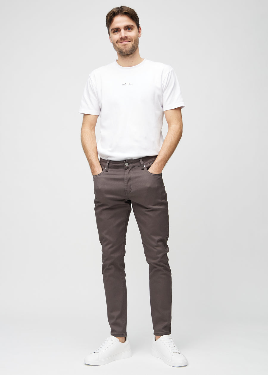 Helbilde av en modell i gråbrune jeans i slim fit.