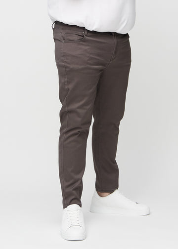 Gråbrune jeans i slim fit, modellnavn Thunders, som sitter tett langs bena på en plus-size-modell, sett forfra.