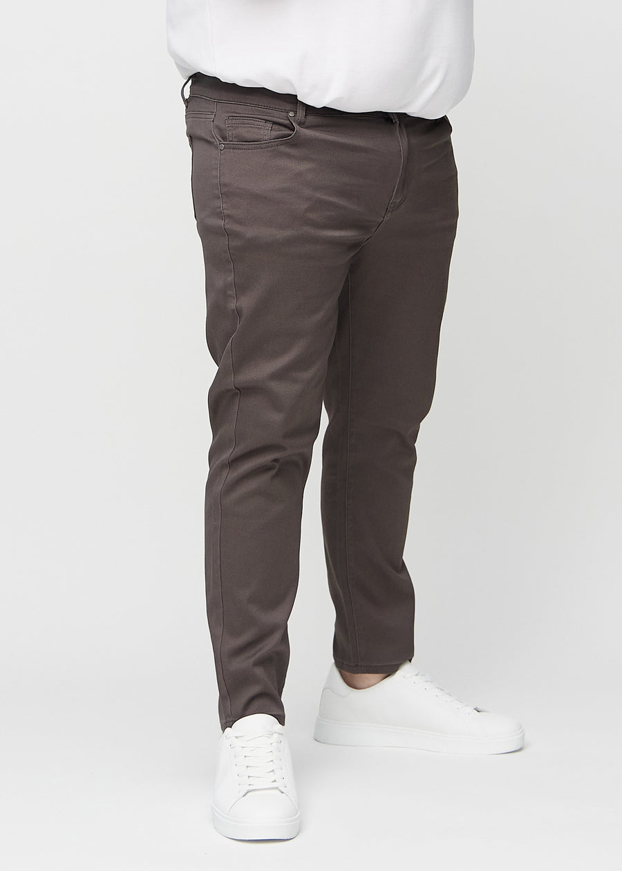 Gråbrune jeans i slim fit, modellnavn Thunders, som sitter tett langs bena på en plus-size-modell, sett forfra.