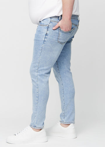 Lyseblå denimjeans i slim fit sett fra siden på en plus-size-modell.