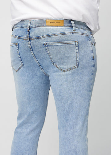 Nærbilde bakfra av lyseblå denimjeans i slim fit på en plus-size-modell som viser detaljer.