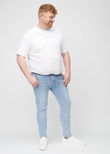 Helbilde av en plus-size-modell i lyseblå denimjeans i slim fit.