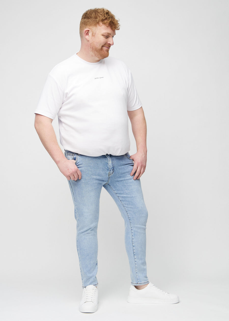 Helbilde av en plus-size-modell i lyseblå denimjeans i slim fit.