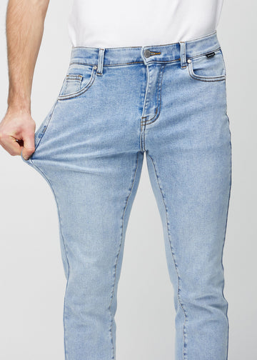 Modell strekker jeansene ved låret for å vise materialets stretch.