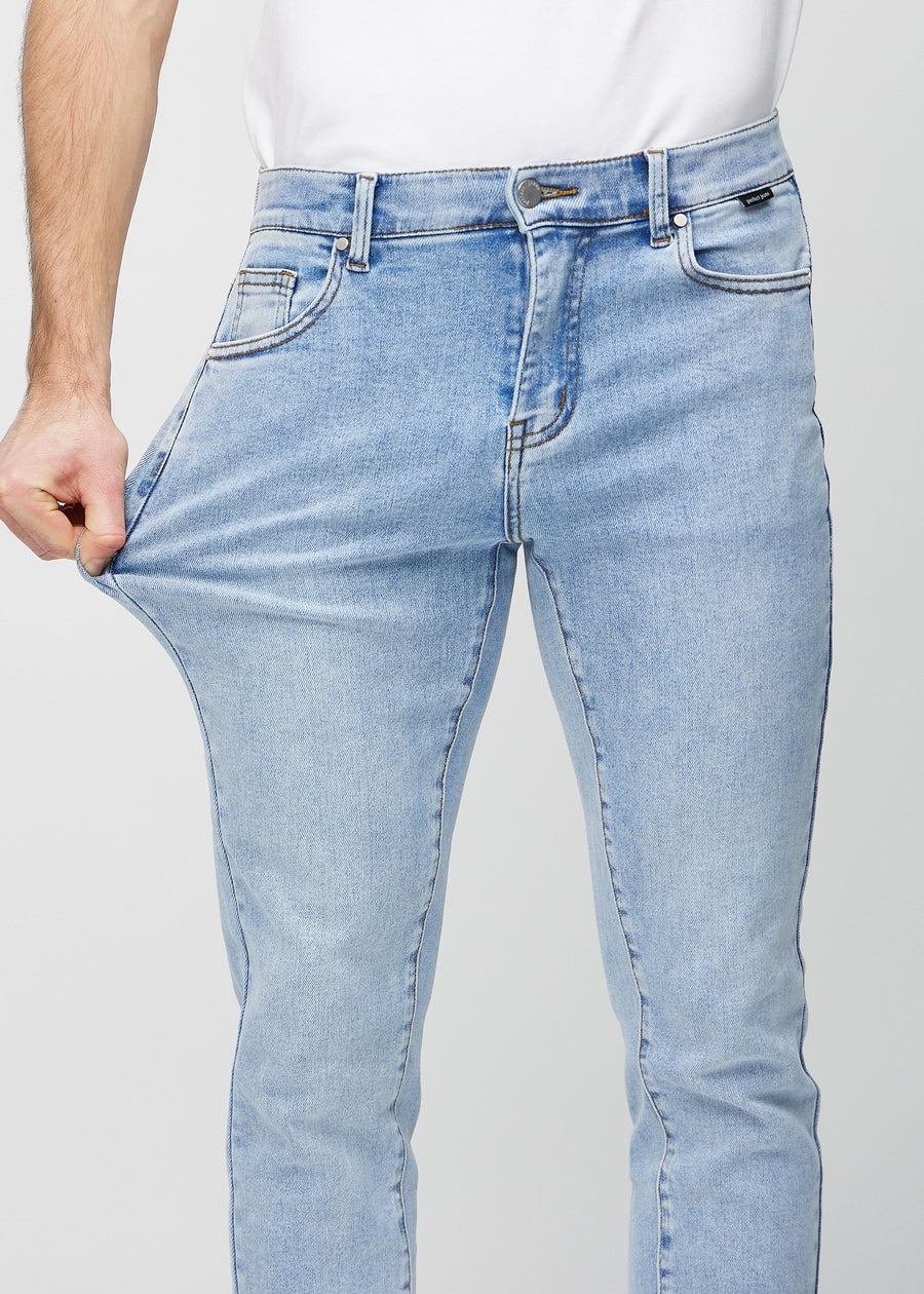 Modell strekker jeansene ved låret for å vise materialets stretch.