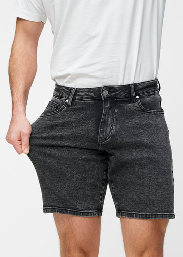Modell strekker mørkegrå denimshorts til herre i fargen Shadows ved låret for å vise materialets stretch.