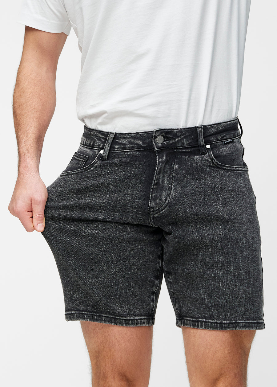 Modell strekker mørkegrå denimshorts til herre i fargen Shadows ved låret for å vise materialets stretch.