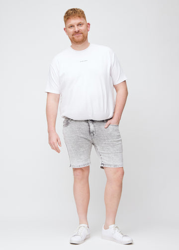 Fullt bilde av en plus-size modell i lysgrå denim middle-slim shorts.