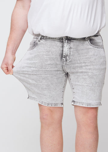 Plus-size modell strekker shortsen ved låret for å vise stretch.