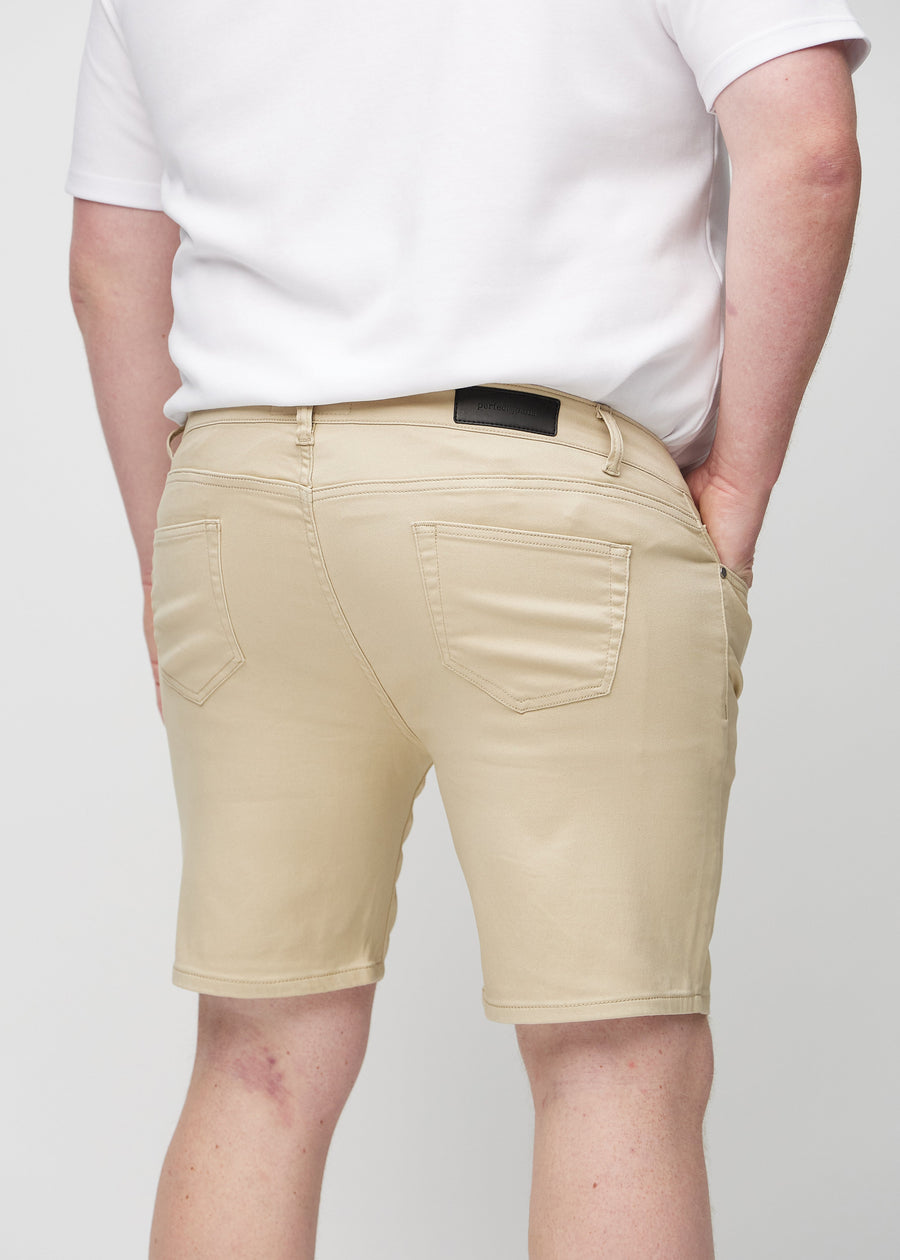 Beige middle-slim shorts sett bakfra på nært hold på en plus-size-modell for å vise detaljer.