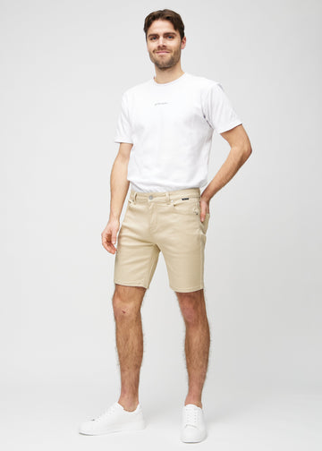 Fullt bilde av modell i beige middle-slim shorts.