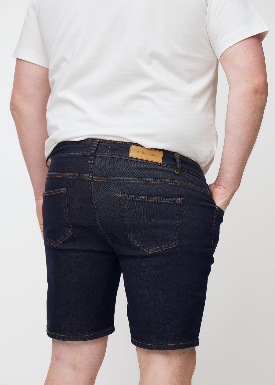 Dyp mørkeblå denimshorts til herre i fargen Midnights sett bakfra i nærbilde på plus-size modell.