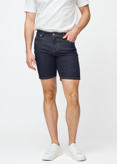 Dyp mørkeblå denimshorts til herre i fargen Midnights med slim passform som sitter naturlig ved hoften og følger lårene tettere enn regular, sett forfra.