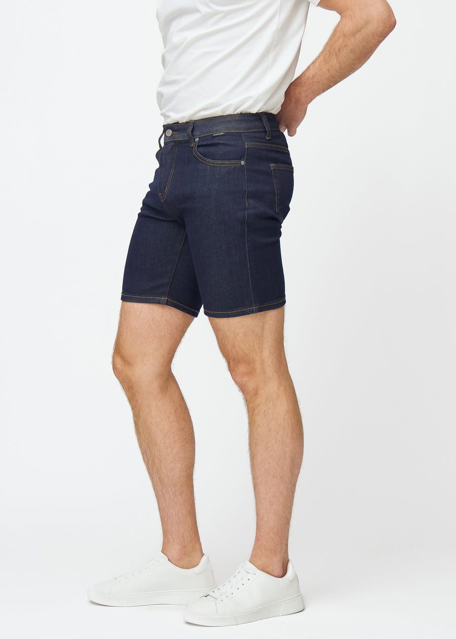 Dyp mørkeblå denimshorts til herre i fargen Midnights med slim passform sett fra siden på modell.