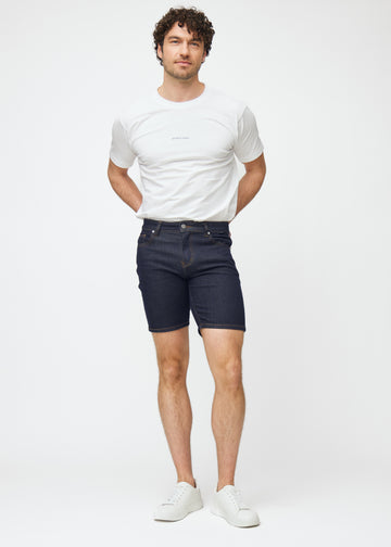 Helbilde av modell i dyp mørkeblå denimshorts til herre i fargen Midnights med slim passform.