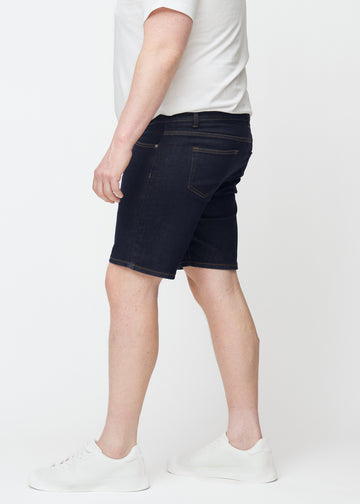 Dyp mørkeblå denimshorts til herre i fargen Midnights med slim passform sett fra siden på plus-size modell.